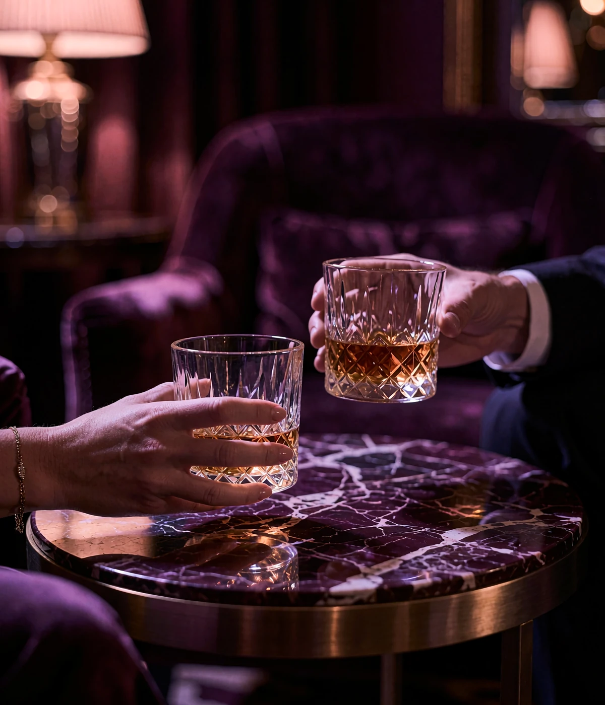 Close view of two crystal whiskey glasses raised in a toast on a marble table inside a private Nashville lounge