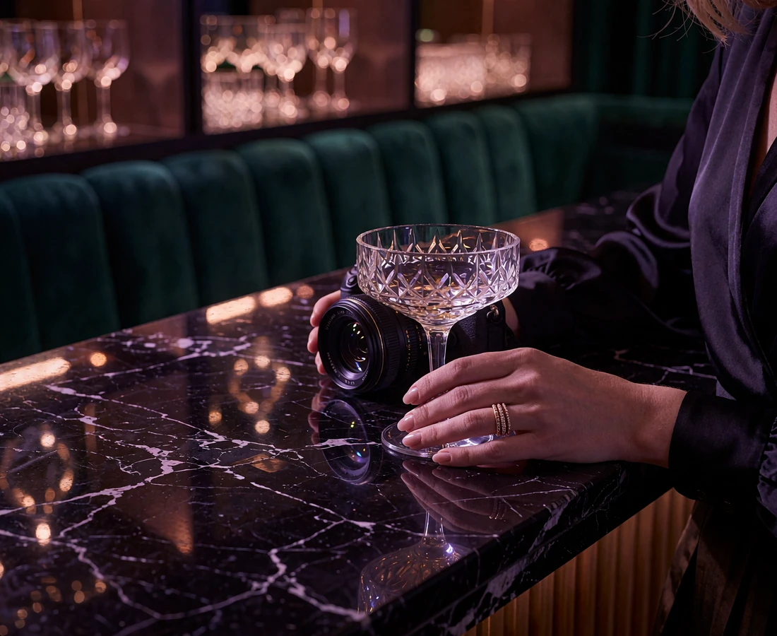 Woman's hand with rose-gold rings resting beside a crystal glass on a polished black marble bar in a Chicago lounge