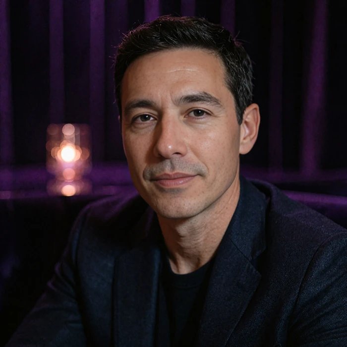 Composed man in his early thirties in a navy jacket with a modest smile in a dim lounge