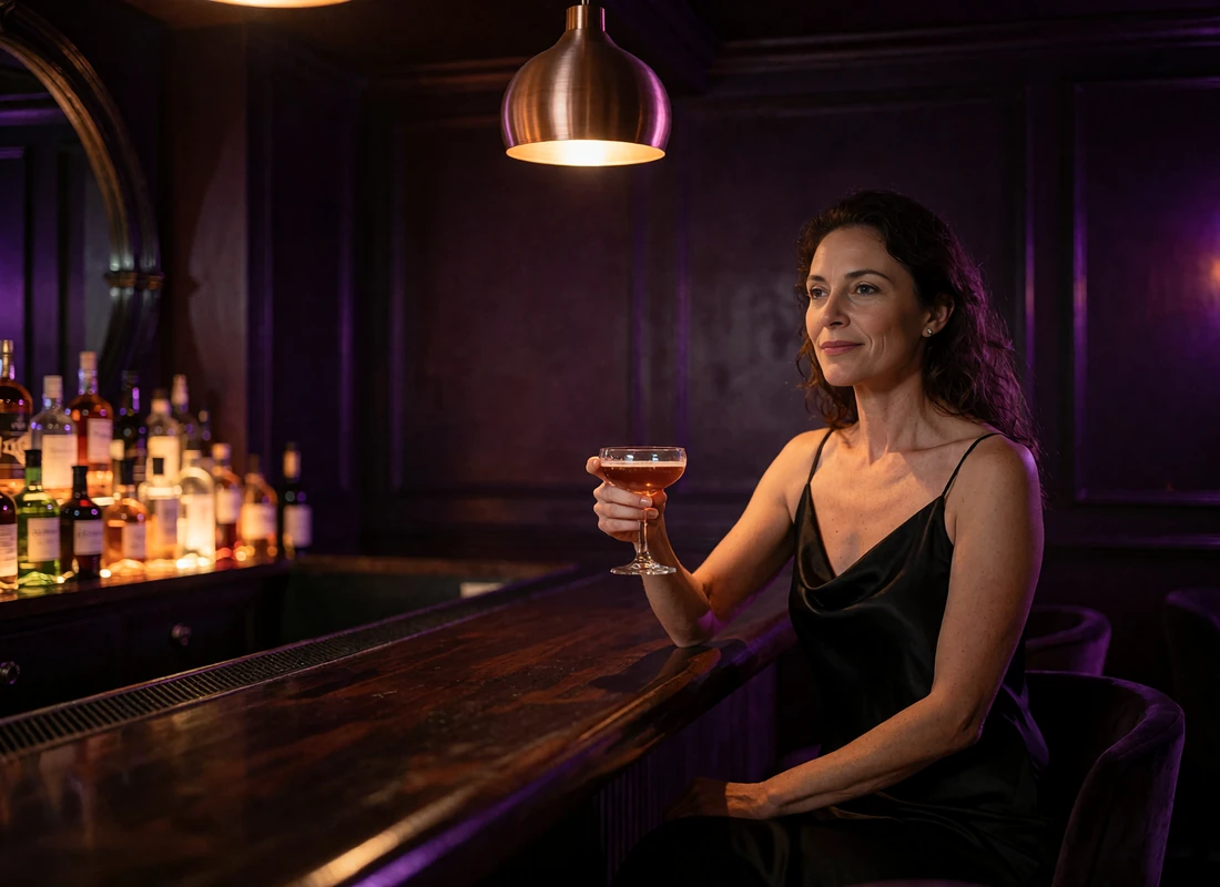 Woman in a black silk dress seated at the bar of a hidden New York speakeasy holding a cocktail
