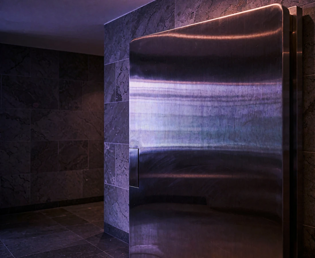Heavy polished steel vault door with a circular locking wheel in a dim corridor, symbolizing member privacy and discretion