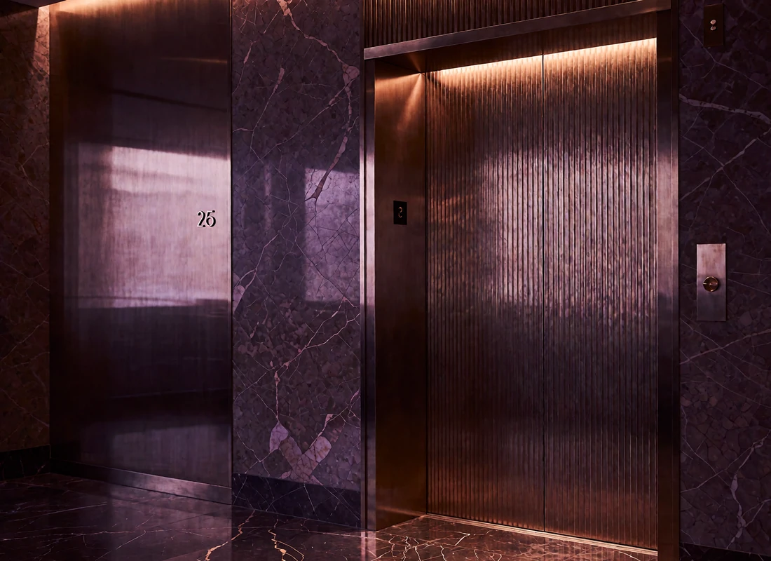 Polished brass private elevator door in a dim, marble-floored Miami penthouse lobby lit by warm concealed lighting